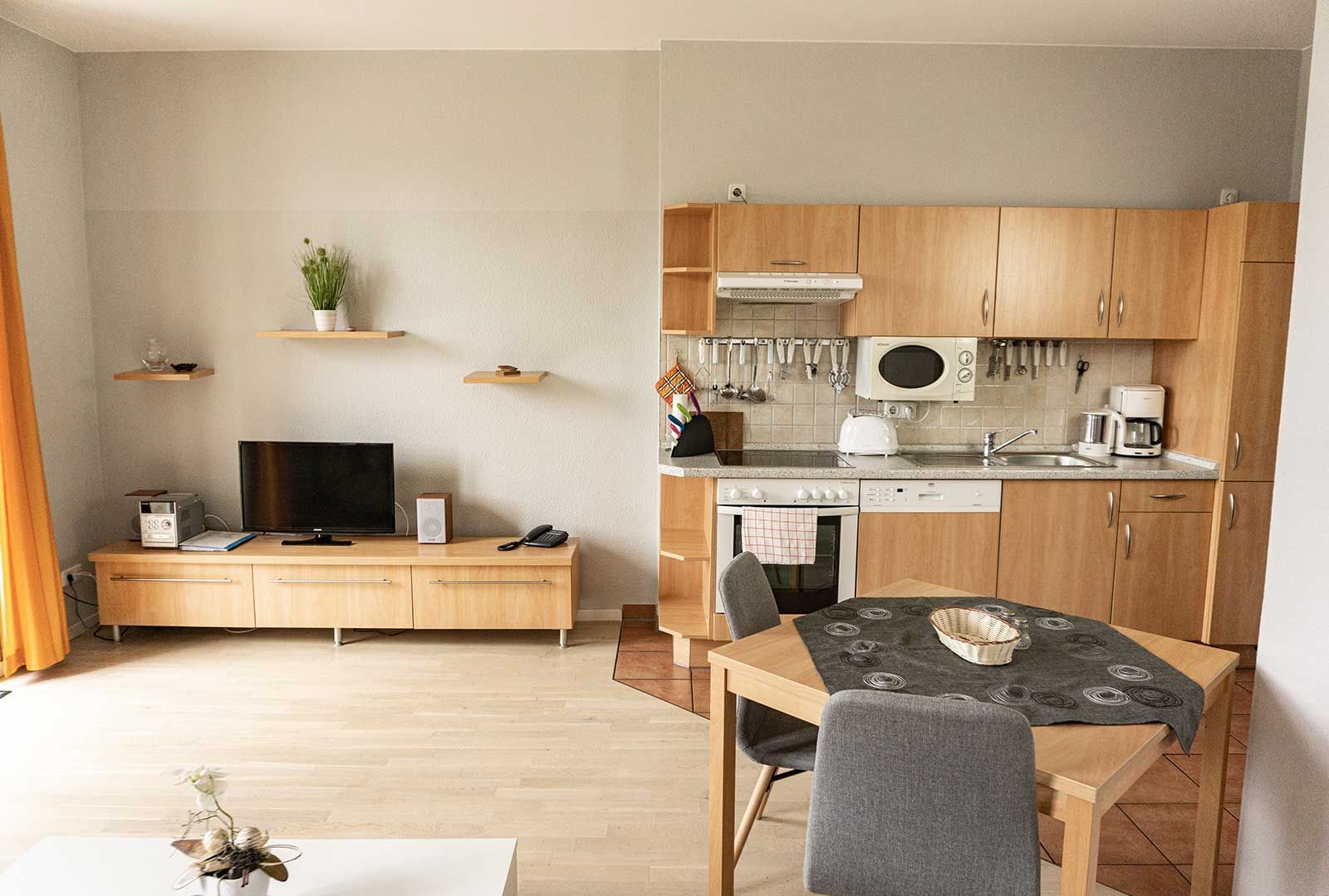 Wohnraum mit TV und offener Küche